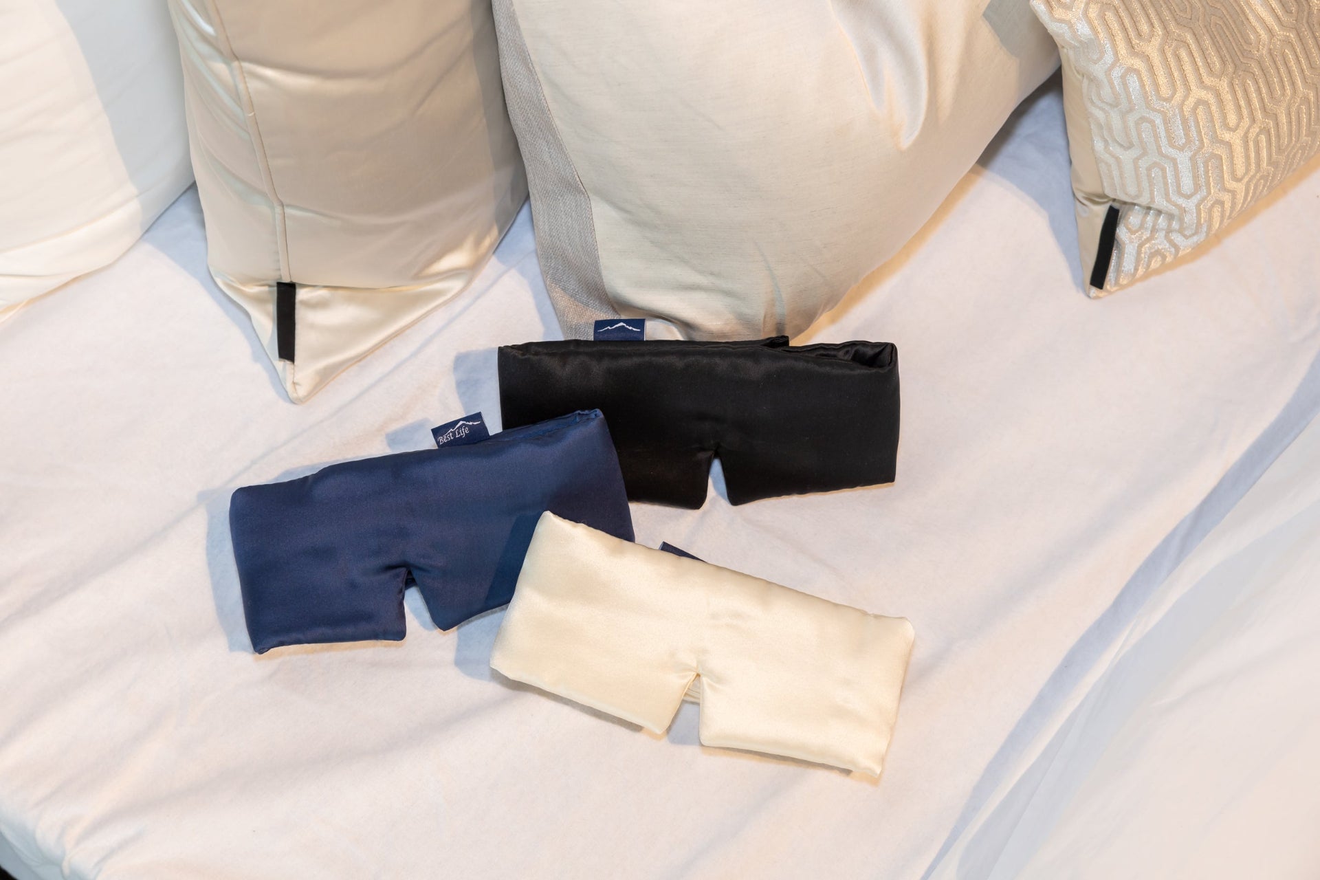 Zijden Slaapmasker Zeya in navy, zwart en crèmewit op bed