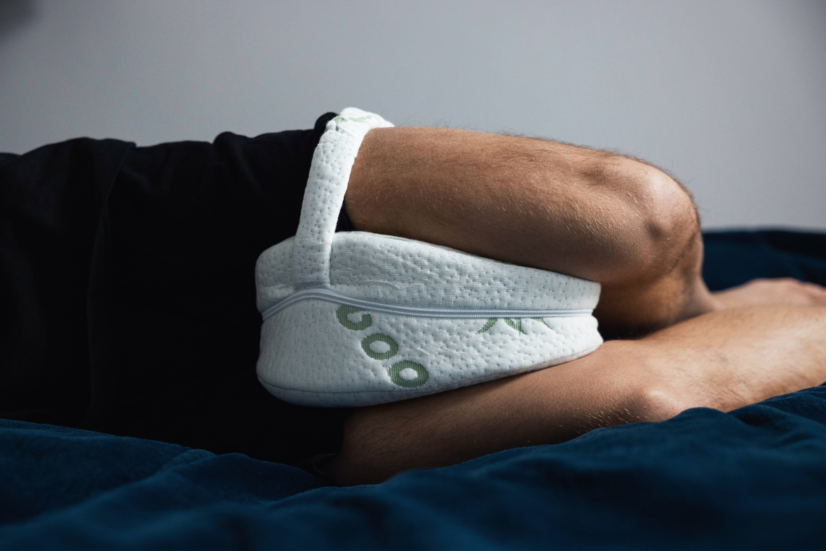 Man slaapt op zijn zij met Kniekussen Mikeno met bamboe hoes tussen de knieën