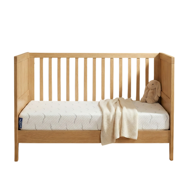 Babymatras Nimba in een houten ledikant met deken